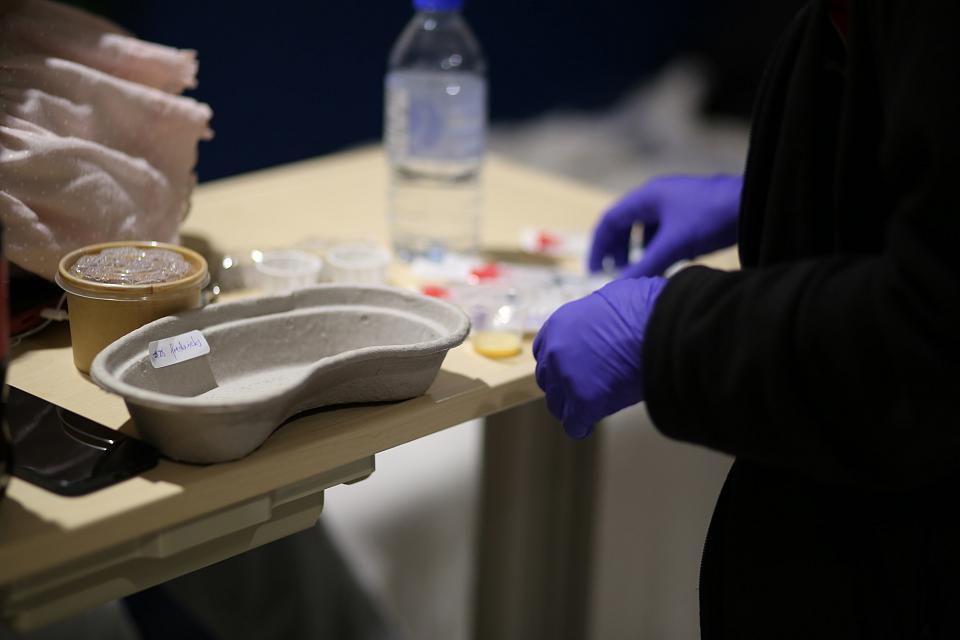 Photographie en plan rapproché montrant les mains d'une infirmière préparant des injections. 