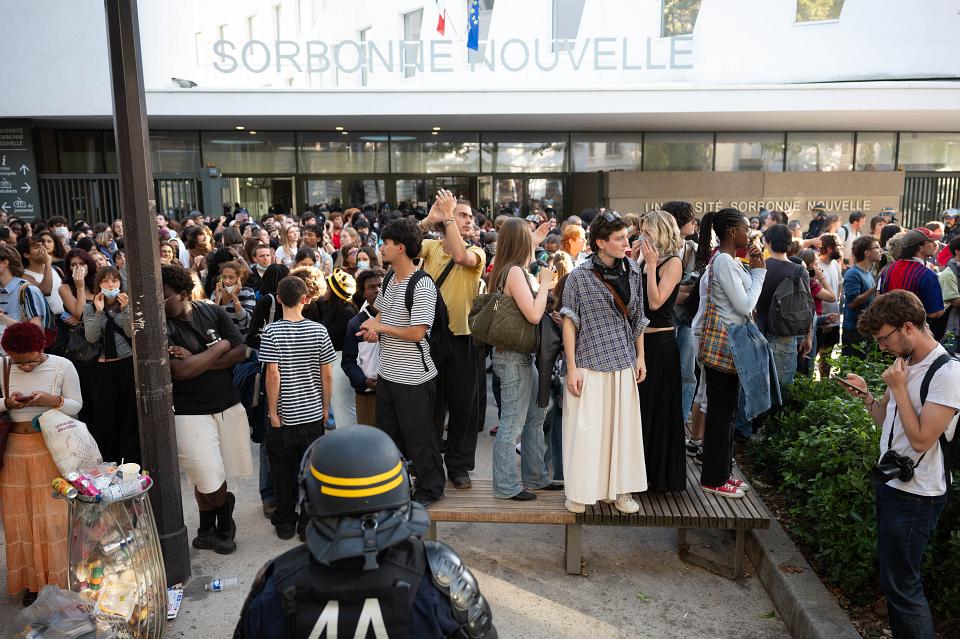 Une foule devant l'université Sorbonne-Nouvelle. Un policier de dos au premier plan. 