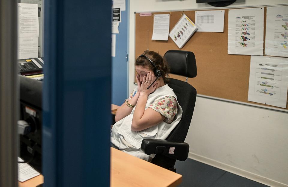 Une femme assiste à un poste de travail avec un casque sur les oreilles se tient le visage entre les mains.