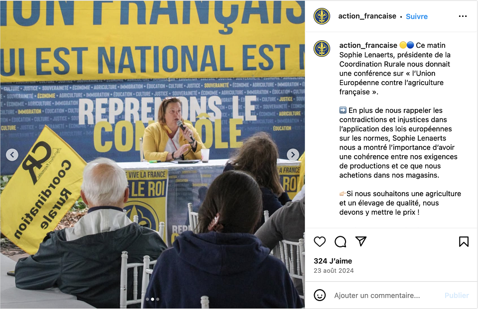 Une femme vêtue de jaune tient un micro devant une assemblée de l'Action Française avec un drapeau de la Coordination rurale