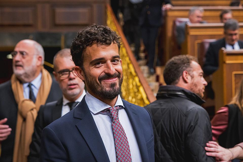 Un homme sourient, en costume. 