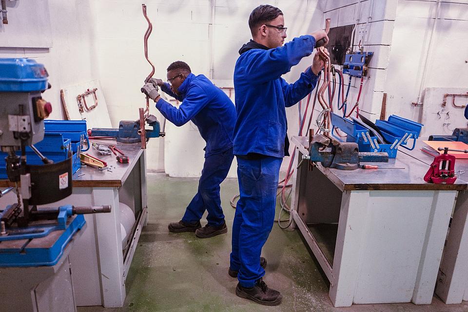 Deux jeunes garçons en bleu de travail examine des tubes de cuivre.