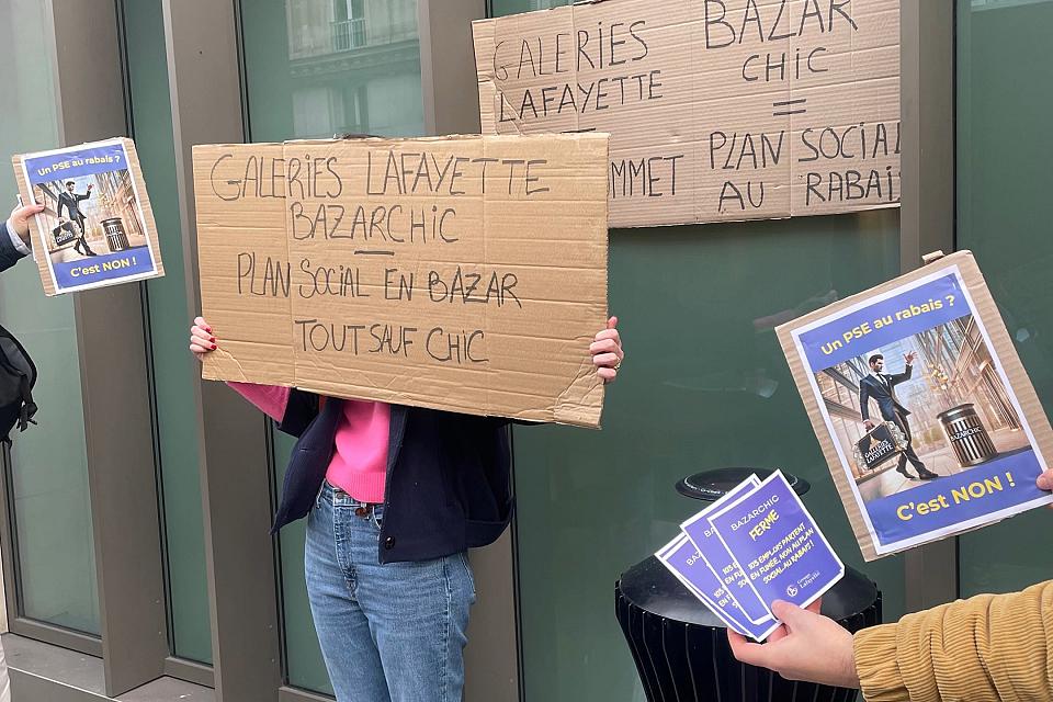 "Plan social en bazar, tout sauf chic" est écrit sur un carton porté par une personne debout qui tient le carton devant son visage. 