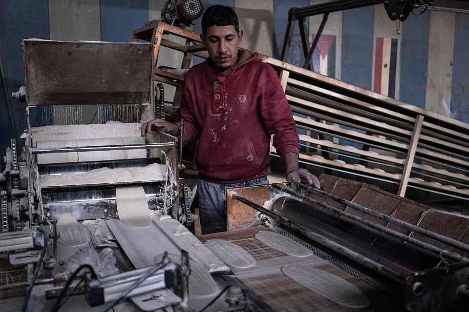 Un travailleur devant la machine faisant défiler la pâte