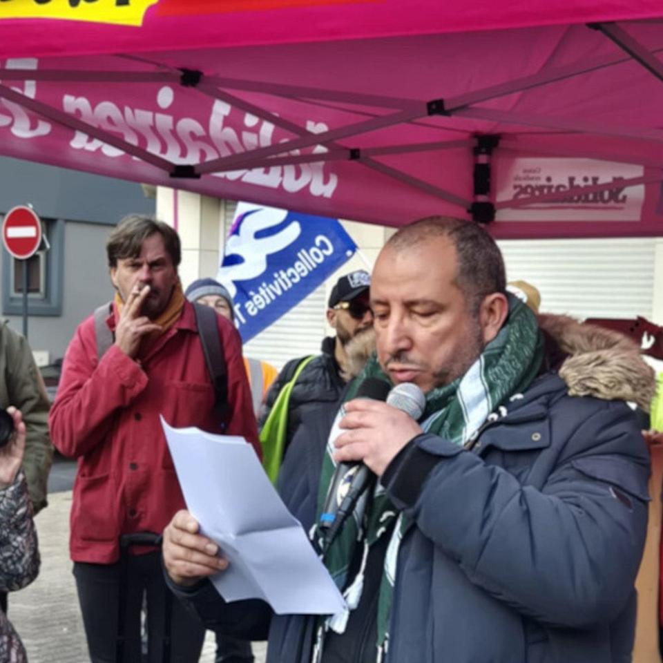 Un homme parle dans un micro lors d'un rassemblement. 