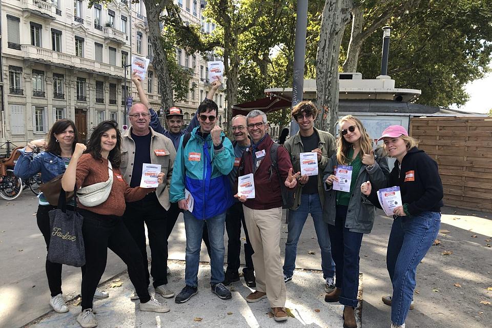 Un groupe de dix personnes souriantes pose en regardant vers l'objectif des tracts à la main. 