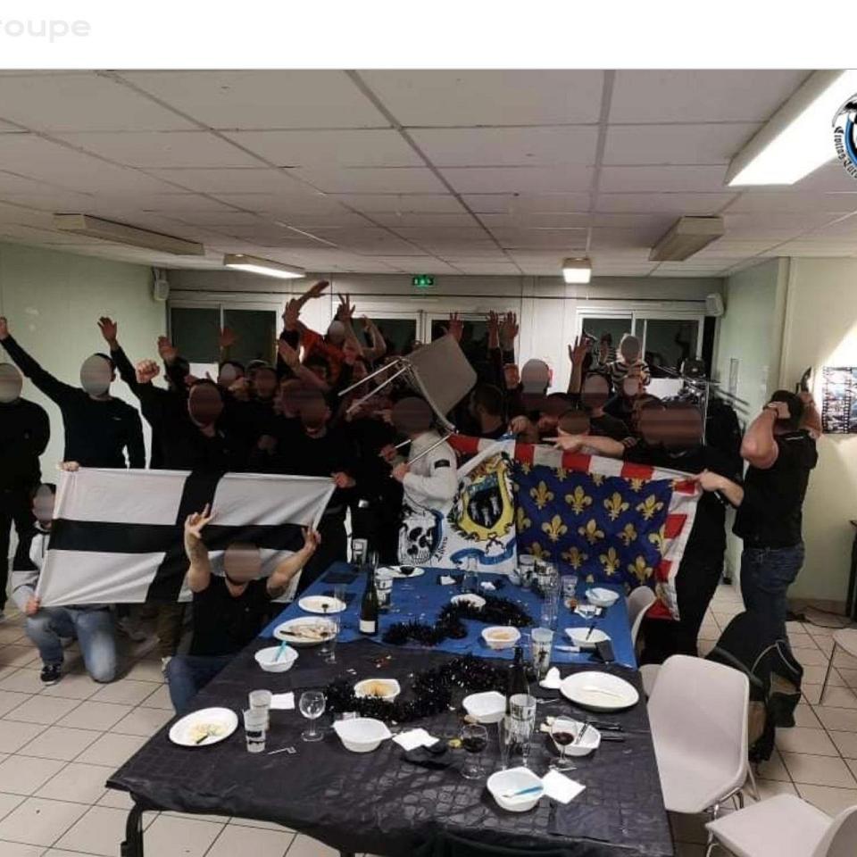 Une trentaine de hooligans rennais et tourangeaux posant derrière leurs drapeaux dans un local