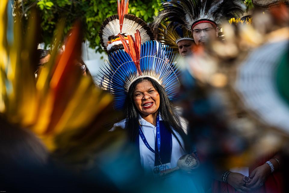 Une femme autochtone, une coiffe de plumes sur la tête.