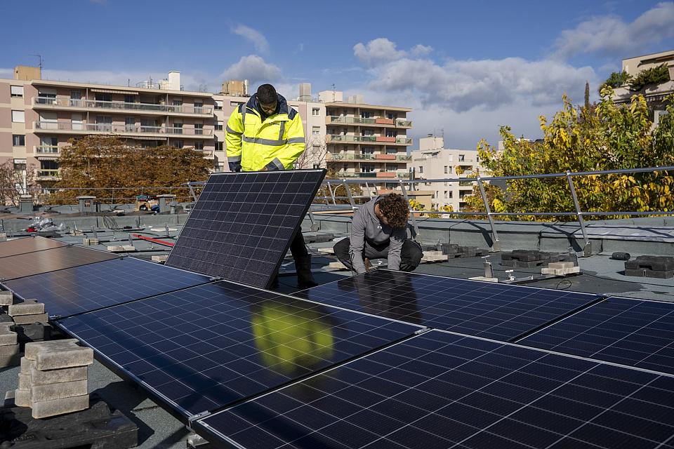  Deux hommes installent des panneaux solaires sur un toit plat.