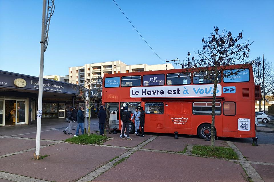 Un bus rouge à deux étages sur un parking, des personnes entrent dans le bus.