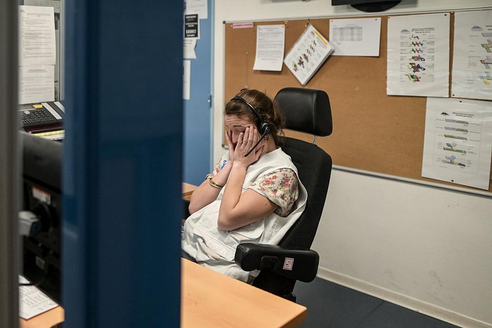 Une femme assiste à un poste de travail avec un casque sur les oreilles se tient le visage entre les mains.