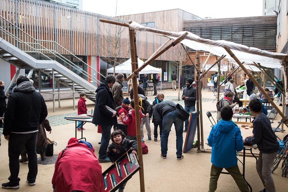 Une cour d'école avec des enfants et des adultes sur une aire de jeux.