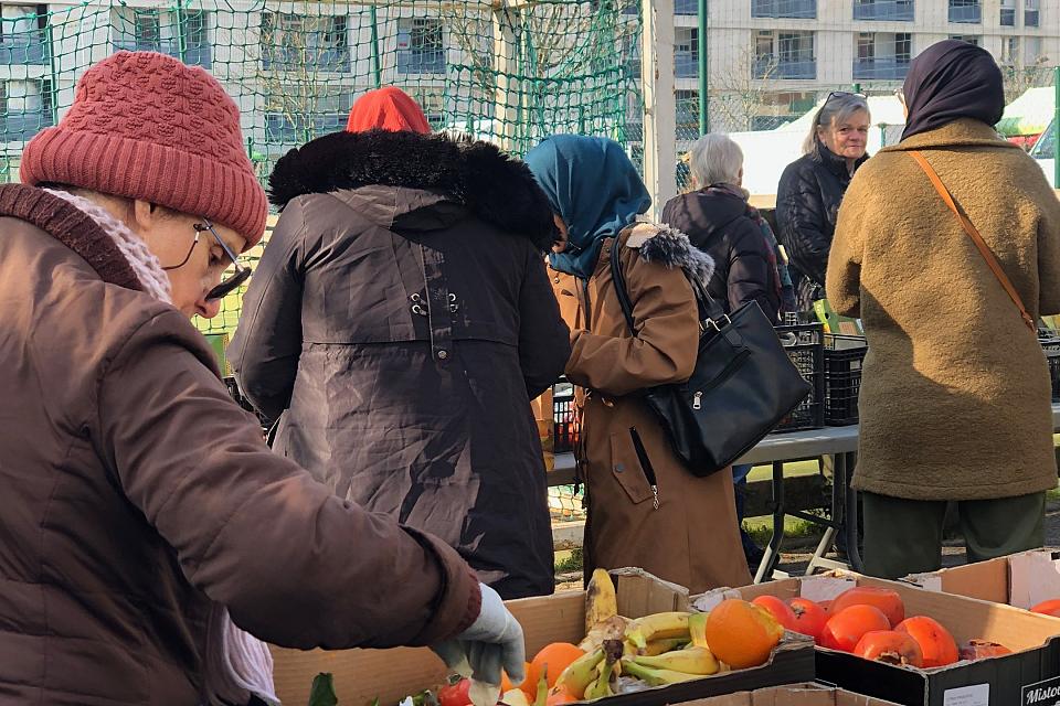 Des personnes autour de cageots de fruits et légumes.