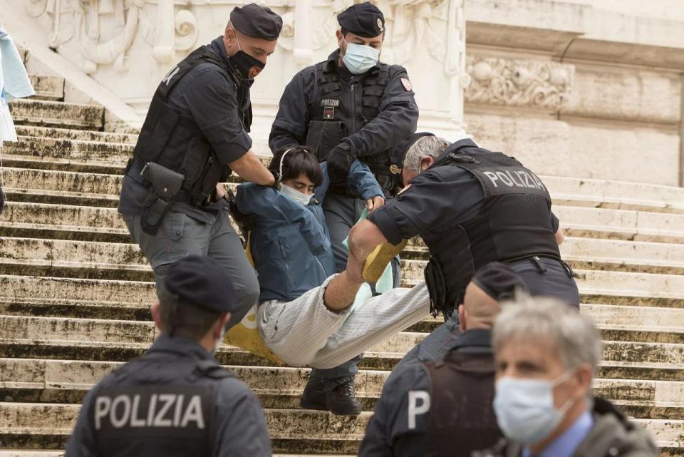 Une personne, un masque sur le visage, portée par trois policiers