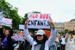 Une femme dans une manifestation brandit une pancarte sur laquelle il est écrit 