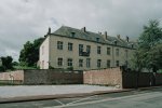 Une très vaste demeure ancienne entourée d'un parc, vue de l'extrérieur, depuis une rue