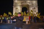 Un homme joue d'un cor devant l'Arc de triomphe à Paris où se tiennent des militants de la Coordination rurale avec des banderoles et drapeaux