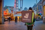 Un livreur avec un sac Deliveroo de dos, avec un fond de maché de Noël