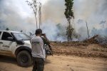 Un homme à côté d'un 4X4, avec le logo de de l'Institut Chico Mendes, filme un feu de forêt 