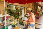 Une femme devant un fleuriste tient un bouquet