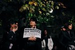 Une manifestante tient une banderole sur laquelle il est écrit « hommage aux victimes de Trappes et la Verrière »