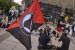 Un drapeau antifasciste tenu par une personne assise par terre