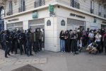 Un groupe d'une quinzaine de policiers avec casques, boucliers, matraques, juste séparé par un angle de rue d'un groupe d'une quinzaine de jeunes manifestants, Place de la Nation.