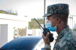 Un homme en tenue militaire de profil tient un talkie-walkie.