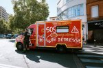 Véhicule de pompiers en grève avec un agent de police et message « SOS Secours En Détresse suite ».