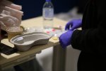 Photographie en plan rapproché montrant les mains d'une infirmière préparant des injections. 