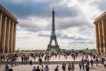Vue du parvis devant la tour Eiifel, plein de monde qui déambule. 