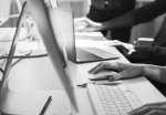 Des mains devant des claviers d'ordinateurs en noir et blanc. 
