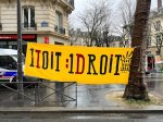 Une banderole jaune accrochée entre deux arbres sur laquelle il est écrit : 1 toit:1 droit