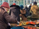 Des personnes autour de cageots de fruits et légumes.