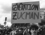 Un homme dans une manifestation tient une pancarte « Génération Zucman », la photo est en noir et blanc. 
