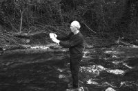 Un homme prélève de l'eau au bord d'une rivière.