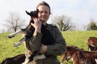 Une femme portant une petite chèvre dans ses bras.