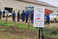 devant des gendarmes dans une ferme, une pancarte est déployée : "l'Etat tue, silence dans les étables"