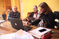 Une femme et deux hommes retraités autour d'un ordinateur et entourés de paperasses
