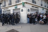 Un groupe d'une quinzaine de policiers avec casques, boucliers, matraques, juste séparé par un angle de rue d'un groupe d'une quinzaine de jeunes manifestants, Place de la Nation.