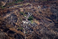 Une photo aérienne de deux hameaux de maisons en partie calcinées au milieu d'un paysage d'arbres eux aussi brûlés.