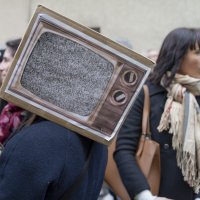 Une manifestante portant une télé en carton avec écran noir